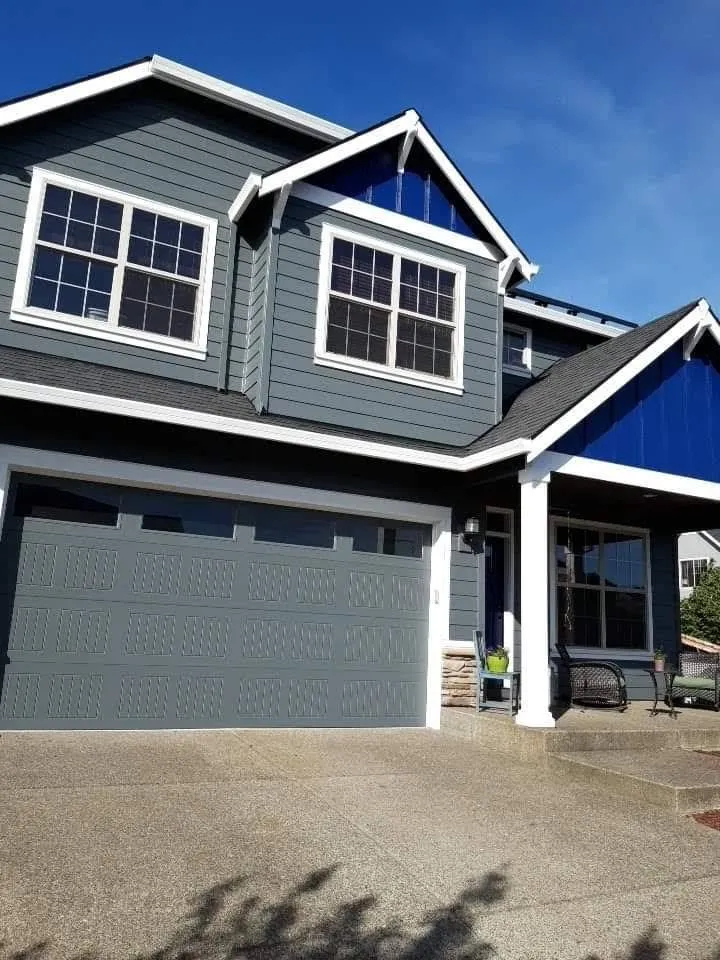 Two-story home painted gray with navy blue accent gables